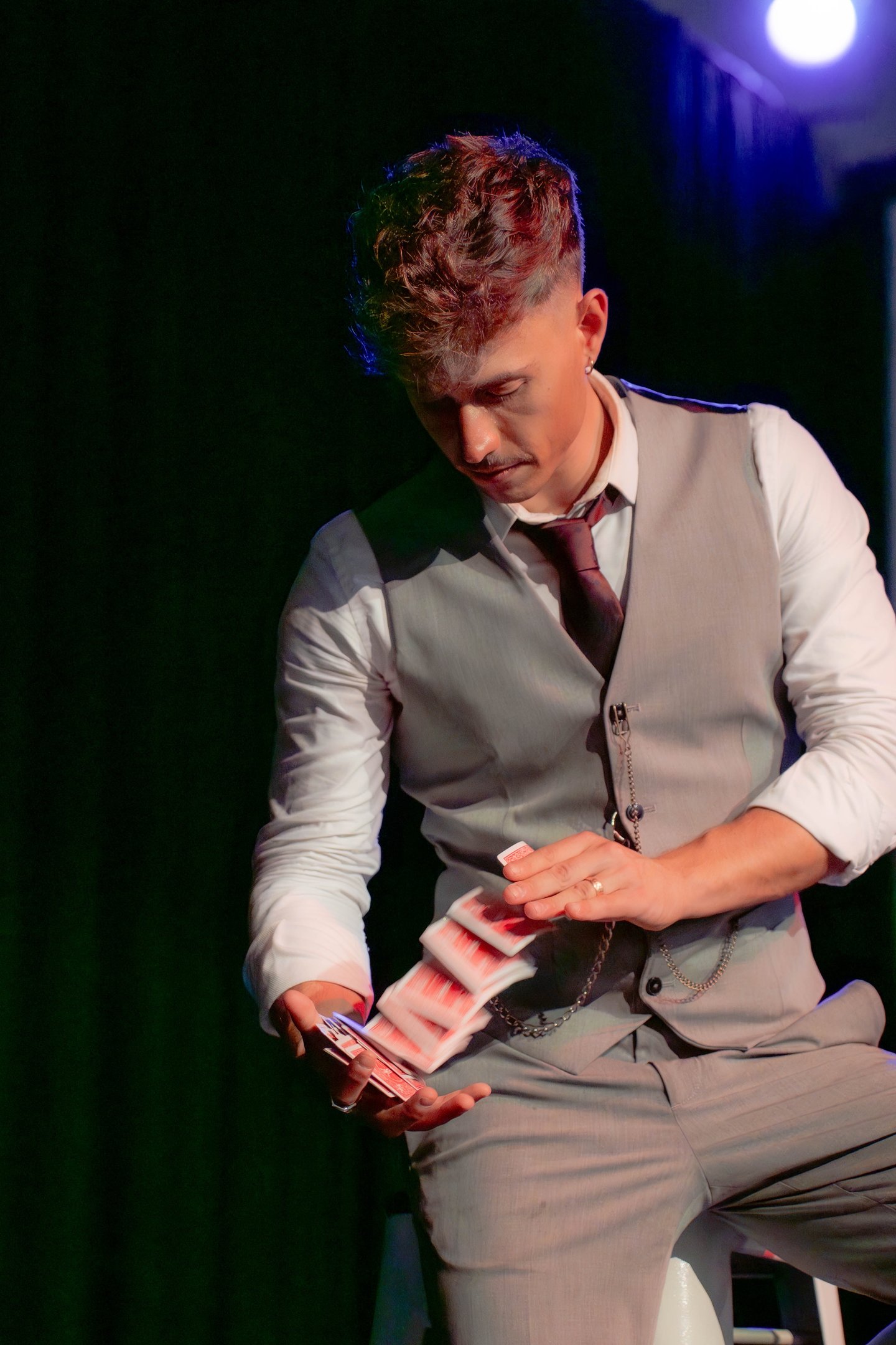 David Maestro mezclando una baraja de cartas bajo focos de escena.